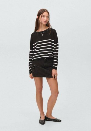 Črno-bela striped pulover, ohlapen kroj, v kombinaciji s črnimi denim krilom, ki ima stranske žepe in zapiranje s pritisnim gumbom, črne balerinke s kili.