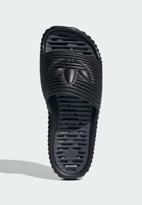 Svart halksandals med texturerad rem och upphöjd logotyp. Ribbad sula för grepp och komfort, minimalistisk design och lättviktsmaterial.