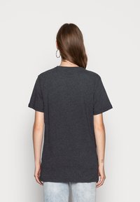 Dark gray cotton t-shirt with short sleeves, round neckline, and a relaxed fit, displayed from the back, paired with light blue jeans.