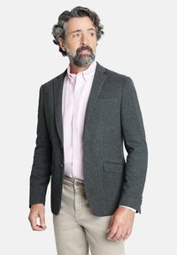 Blazer gris de espiga con solapas de pico, dos bolsillos frontales y cierre de un botón, usado sobre una camisa de botones rosa claro.
