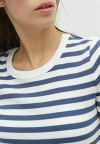 Camisa de rayas en navy y blanco, textura acanalada, con cuello redondo, presenta rayas horizontales espaciadas uniformemente, la tela parece suave.