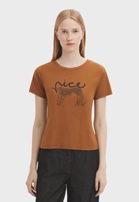 Brun kortærmet T-shirt med runder hals og et grafisk print af et leoparddesign sammen med ordet "nice" i sort. Blødt bomuldsstof.