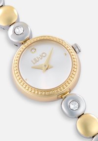 Montre bracelet en or et en argent avec un cadran blanc, dotée d'une lunette en or perlée, de mains dorées et d'un accent en cristal à 12 heures.