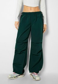 Baggy, mörkgröna byxor i lätt material, med elastisk midja, sidofickor och avslappnad passform.