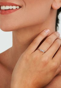 Silberring mit drei klaren, runden Steinen, auf einem schlanken Band gesetzt. Glatte Textur, die ein minimalistisches Design zeigt.