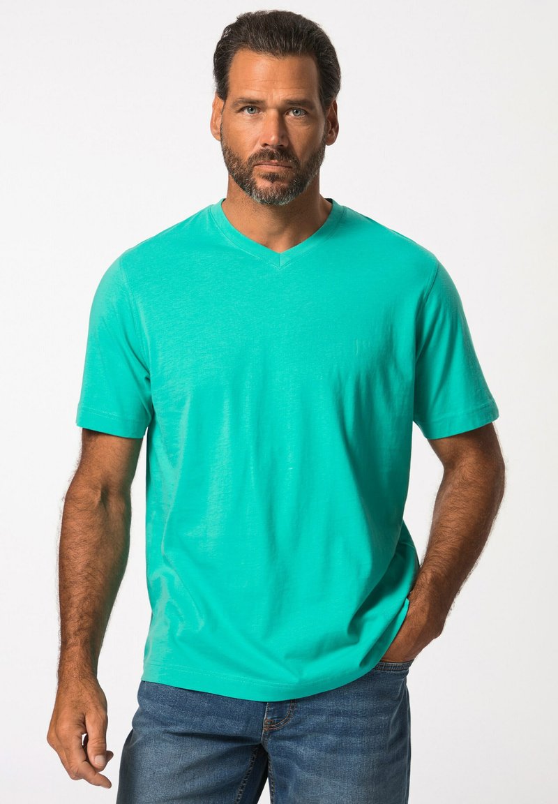 Camiseta de algodón turquesa de manga corta y escote en V, hecha de una tela suave, que presenta un corte relajado y una textura lisa. Combinada con pantalones vaqueros.