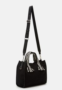 Černá obdélníková kabelka se širokými černobílými pruhovanými uchy a nastavitelným černým ramenním popruhem s kovovými sponami.