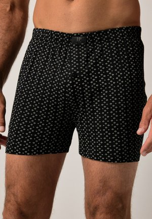 Schwarze Boxershorts mit einem weißen geometrischen Muster, elastischem Bund und Knopfleiste. Hergestellt aus weichem Material mit glatter Textur.