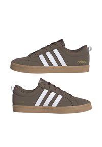 Par de zapatillas Adidas marrones con rayas blancas, suelas beige, cordones y logo dorado de Adidas en los talones, mostradas en vistas laterales.