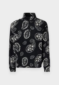 Svart og hvit paisley-mønstret fleece-pullover med halv-glidelås krage og lange ermer, med en teksturert og myk overflate.