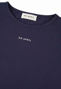 Marineblauwe t-shirt van zachte katoen met een ronde hals. Voorzien van geborduurde witte tekst "OH APRIL" op de borst.
