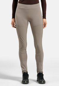 Beige Outdoor-Hosen mit mittelhohem Bund, seitlichen Reißverschlusstaschen und verstärkten Kniepartien. Das Material ist leicht und dehnbar.