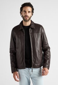 Braune Lederjacke mit Kragen, durchgehendem Reißverschluss und zwei Seitentaschen. Die glatte Textur und die sauberen Nähte betonen das Design.