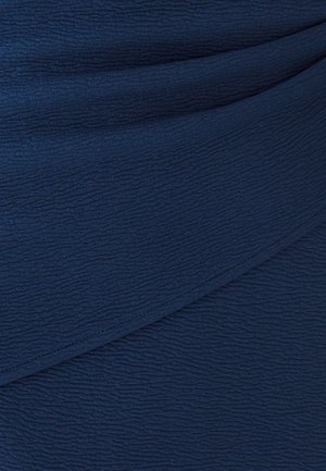 Tela texturizada azul marino, con un sutil patrón arrugado. Caída suave con diseño en capas, proporcionando profundidad y dimensión al material.