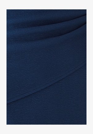 Tela texturizada azul marino, con un sutil patrón arrugado. Caída suave con diseño en capas, proporcionando profundidad y dimensión al material.