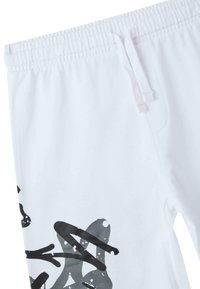 Pantaloni della tuta bianchi con vita elastica, caratterizzati da schemi astratti neri e dettagli macchiati lungo il lato, realizzati in morbido cotone.