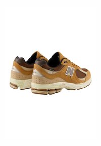 Baskets en daim marron avec des accents en maille, dotées d'une semelle épaisse, de motifs texturés et du logo "GORE-TEX" sur le côté.