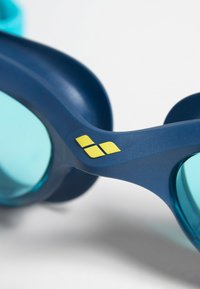 Blauwe zwembril met teal lenzen, voorzien van een gladde plastic frame en een gele logo op de neusbrug. Zachte rubberen randen voor comfort.