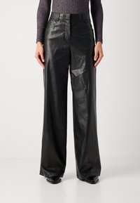 Pantalons larges en cuir noir avec une texture lisse, poches avant et passants de ceinture, présentant un design taille haute.