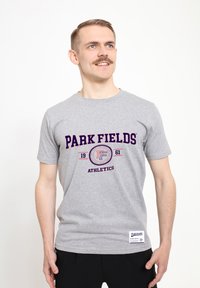 Grå bomulds t-shirt med "PARK FIELDS ATHLETICS" grafik i marineblå og rød. Klassisk rund hals, korte ærmer, med et logo mærke på kanten.