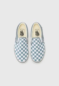 Zapatillas slip-on con un patrón a cuadros en azul y blanco, suela de goma blanca y cuello acolchado para mayor comodidad. Logo de Vans en la plantilla.