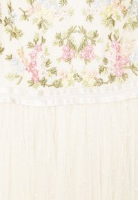Bílé šaty s květinovou výšivkou v pastelových barvách, s texturovaným korzetem a měkkou, vrstvenou tylovou sukní. Saténový lem v pase.