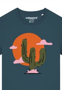 Teal T-Shirt mit einem runden Kaktus-Graphic in Grün mit braunen Akzenten, vor einer orangefarbenen Sonne und rosa Wolken.