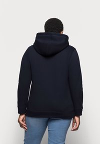 Tmavě modrá mikina s kapucí na stahovací šňůrku, dlouhými rukávy a žebrovaným lemem. Měkká látka s hladkou texturou a minimálním množstvím švů.