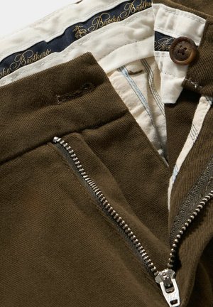 Pantaloni in cotone marroni con zip frontale, cintura color crema con quadretti blu e un bottone con il marchio "Brooks Brothers".