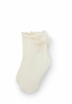 Kremowe skarpetki do kostki z falbanką z koronki i małą ozdobną kokardką na każdym mankiecie, pokazane na białym tle.