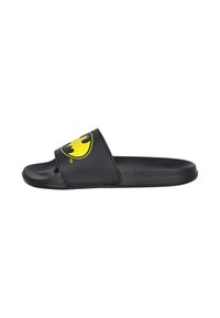 Sandalia plana negra con suela plana y tira ancha que presenta el logotipo amarillo de Batman. Fabricada en material sintético suave con un acabado mate.