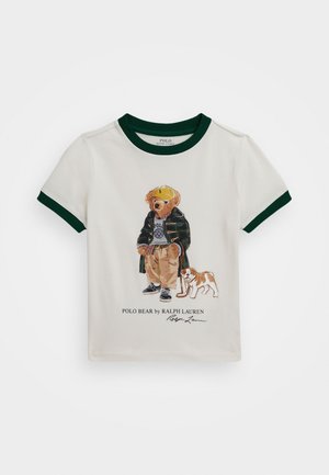 Weißes Baumwoll-T-Shirt mit grünen Akzenten, das in der Mitte einen cartoonhaften Bären in einer Jacke und mit einer Mütze neben einem Hund zeigt.