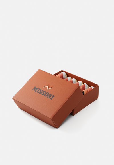Brown cardboard box with "MISSONI" logo, containing colorful zig-zag patterned items. Box has a distinctive, angled lid and smooth texture.