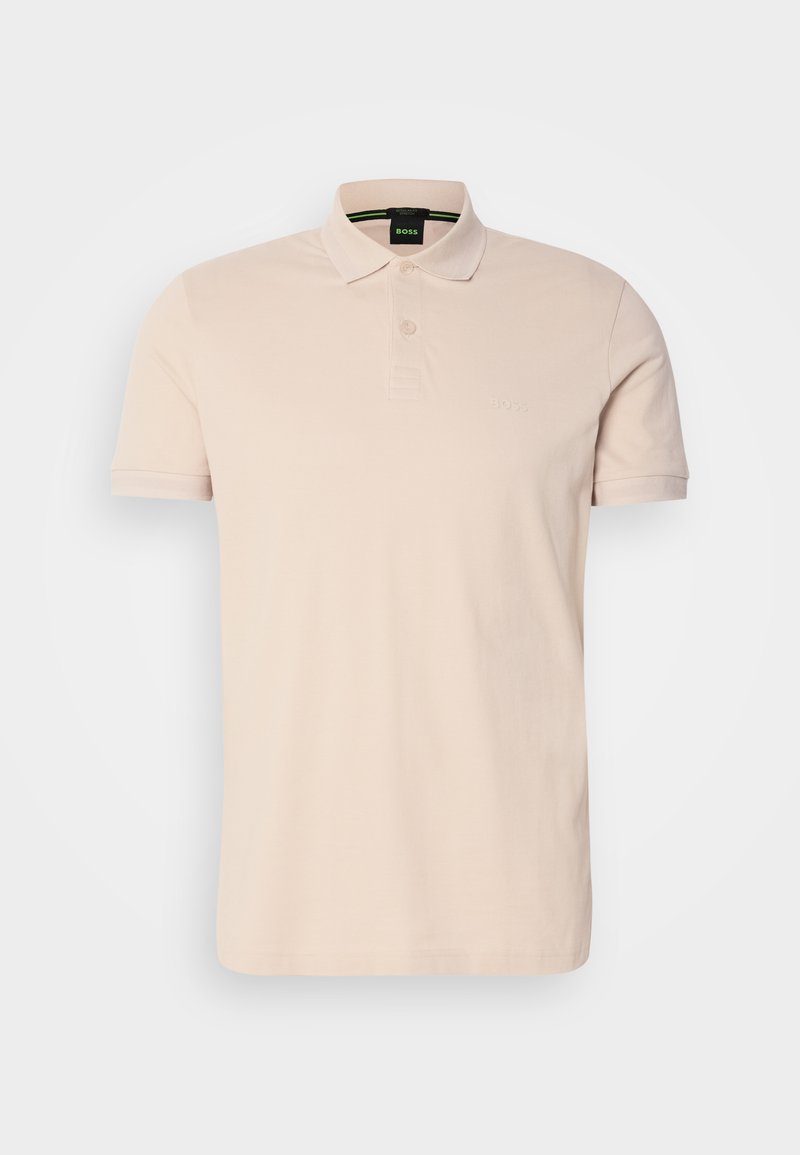 Polo shirt beige clair en coton. Il comporte une patte de boutonnage à trois boutons et des manches courtes, avec un logo de marque brodé sur la poitrine.