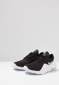 Černé sportovní tenisky s síťovaným svrškem, bílou gumovou podrážkou, zaoblenou špičkou a výrazným logem Nike. Obsahují polstrovaný límec a poutko na patě.