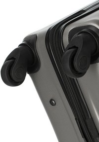 Harde koffer met een gemêleerd grijs exterieur, zwarte ritsen en dubbele wielen voor gemakkelijke mobiliteit. Voorzien van een stevige handgreep en duurzame hoeken.
