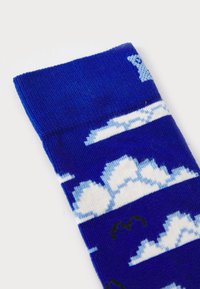 Blue knitted sock featuring white cloud patterns, alternating with solid blue stripes. Textured fabric with a ribbed cuff.