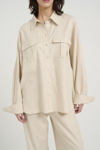 Chemise beige à boutons avec col, deux poches poitrine et manches longues. Fabriquée en tissu léger avec une coupe décontractée et des poignets repliables.