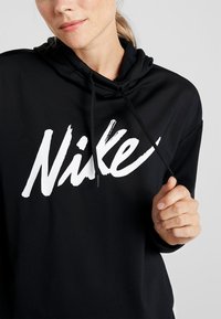Felpa nera con cappuccio e lacci, con un grande logo Nike bianco. Realizzata in materiale morbido, è caratterizzata da una vestibilità rilassata e maniche lunghe.