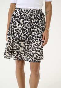 Jupe plissée à plusieurs niveaux en imprimé léopard noir et blanc avec une taille élastique. Tissu transparent avec un design fluide et en couches.