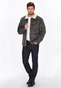 Herre grå ternet jakke med sherpa krave, udstyret med forlommer, parret med mørke jeans og sorte snørebåndsstøvler.