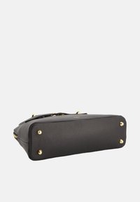 Black leather handbag with a textured finish, gold hardware accents, and four metal feet on the base for stability.