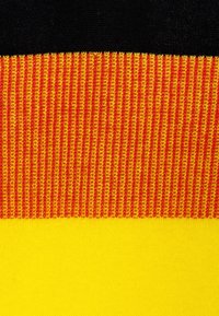Textil con tres franjas horizontales: negro en la parte superior, rojo y naranja acanalado en el medio, y un fondo amarillo liso. Textura suave en general.