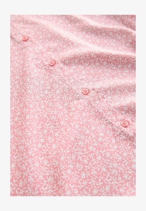 Rozā krekls ar ziedu baltiem rakstiem, priekšpusē ar rozā pogām. Gluda auduma ar vieglu tekstūru.