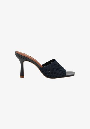 Sort mule-sandal med høj hæl, flettet overdel, åben tå og slank hæl, vist fra siden på hvid baggrund.