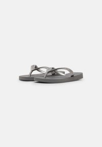 Infradito grigi con cinturino textured e suola piatta, caratterizzati da un design semplice e un logo sottile sul cinturino.