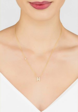 Gold-tone necklace with a delicate chain featuring a Pisces symbol pendant adorned with white crystals. Smooth surfaces, minimalistic design.