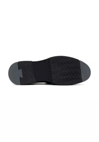 Suela de zapatilla negra con goma texturizada para agarre, que presenta una tapa de talón gris suave y un patrón de banda de rodadura en zigzag para tracción.