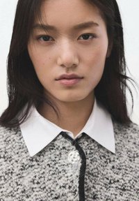 Džemper od mješavine vune u sivoj boji s teksturiranim uzorkom, s bijelim ovratnikom košulje i vidljivim detaljem gumba u sredini.