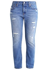 Džínové kalhoty v modré barvě s opotřebeným vzhledem, středním pasem, s protrženinami na přední straně, jemným vyblednutím a rovnými nohavicemi.